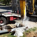 Hammer attachment on the end of an excavator hammering away a concrete slab.