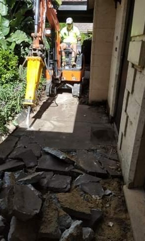 Mini excavator with rock hammer breaking concrete in Darwin